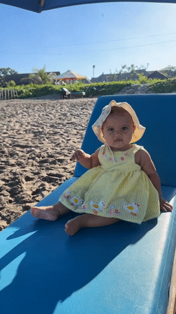 Baby in yellow dress enjoys beach time in North Kuta