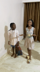 Three girls dance together in residential room in Jos