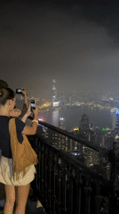 Tourists photograph Hong Kong skyline from Victoria Peak viewpoint