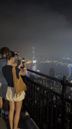 Tourists photograph Hong Kong skyline from Victoria Peak viewpoint