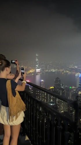 Tourists photograph Hong Kong skyline from Victoria Peak viewpoint