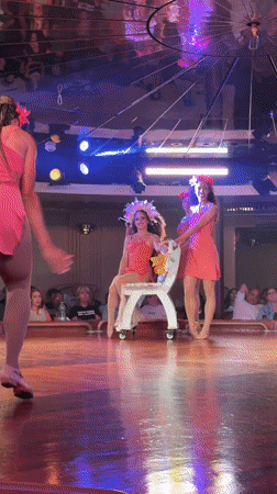 Pink-clad performers dancing on stage, arms raised.