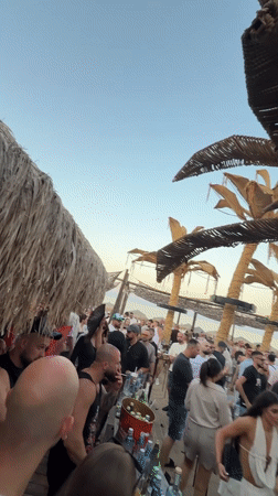 Beach party crowd gathers under thatched roof in Sozopol