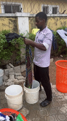 Man hand-washes clothes outdoors in Abuja residential area
