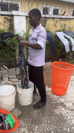 Man hand-washes clothes outdoors in Abuja residential area