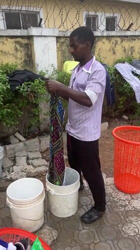 Man hand-washes clothes outdoors in Abuja residential area