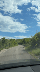 Vehicle drives rural Montenegro road amid green countryside scenery