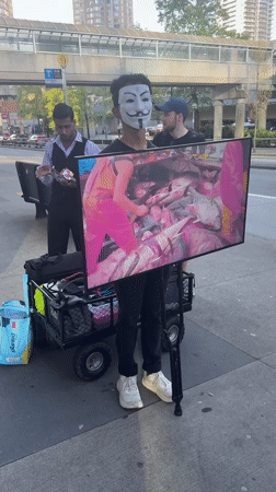 Masked protester displays fish processing footage on Burnaby sidewalk