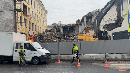 Workers clean road debris after building demolition