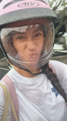 Woman films herself riding motorcycle in rain in Kuta Selatan