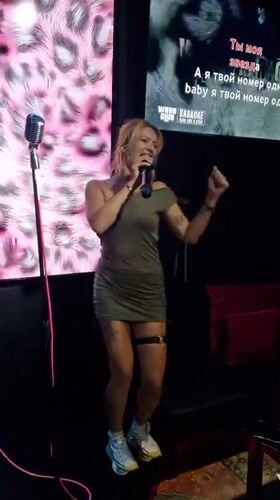 Woman performs karaoke in dimly lit Thai venue