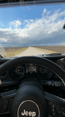 Jeep travels rural road through countryside fields