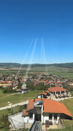 Funicular passenger records scenic village with red roofs, mountains