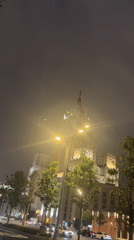 Illuminated skyscraper observed on foggy night street scene