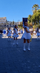 Youth marching band parade in white-blue uniforms with batons