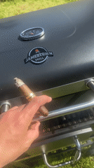 Person grills food while smoking cigar in Dimchevo, Bulgaria