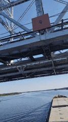 Tugboat pushes loaded barge under bridge on unidentified river