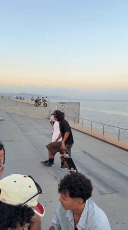 Young men skateboard near Barcelona waterfront during sunset session