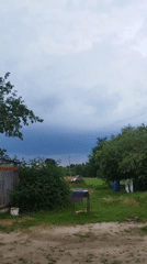 Storm clouds gather over a rural Belarusian yard in summer