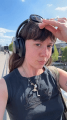 Woman films selfie video by Thames on sunny London afternoon