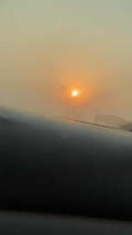 The video shows a car's dashboard with a foggy sunrise visible through the windshield. A streetlight is also visible through the fog. The car appears to be moving.