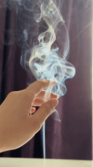 Person burns incense, plays with smoke in decorated room