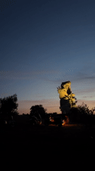 Illuminated bird sculpture draws motorcycle visitors at Indonesian dusk