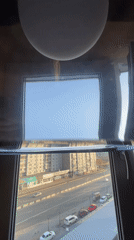 Water-filled window creates distorted cityscape reflections in Krasnoyarsk room