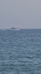 Busy afternoon on Quarteira beach, boats offshore