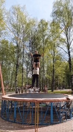 Bungee-harnessed person held on shoulders during trampoline activity