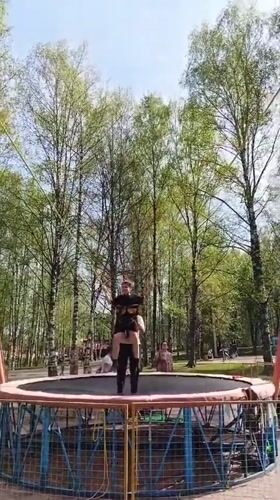 Bungee-harnessed person held on shoulders during trampoline activity