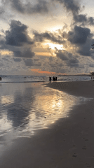 Beachgoers wade in sunset waters along Sri Lankan coast