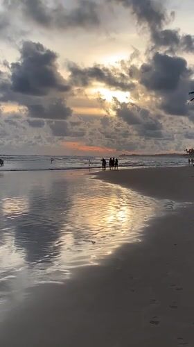 Beachgoers wade in sunset waters along Sri Lankan coast