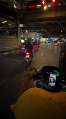 Motorcyclist rides through wet Bangkok streets at night