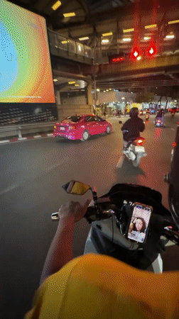 Motorcyclist rides through wet Bangkok streets at night