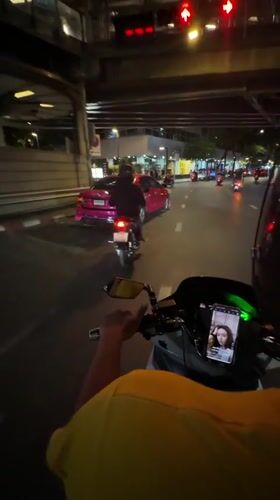 Motorcyclist rides through wet Bangkok streets at night