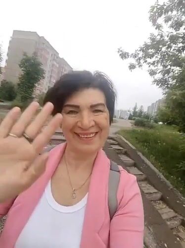 Woman waves at camera in Krasnoyarsk street scene