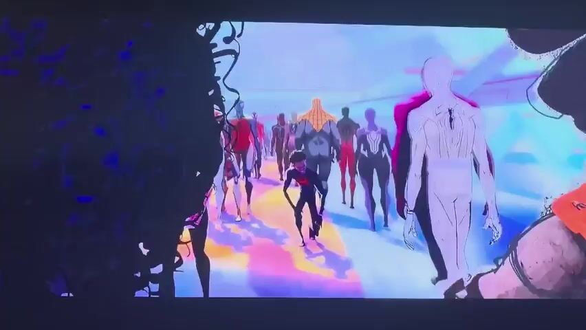 The media file shows a scene from an animated movie, featuring a large group of characters dressed as Spider-Man. The characters are diverse in appearance, with variations in their costumes and some appearing to be different species or genders. They are walking through a futuristic, brightly lit environment with geometric architecture and colorful, glowing pathways. The scene appears to be set during the day, with the bright lighting suggesting an indoor or artificial environment rather than natural sunlight.

The Spider-Man characters are carrying various objects, some of which appear to be advanced technology or weapons, suggesting they are part of an organized group or mission. The overall mood is one of action and suspense, with the characters moving with purpose. Some individuals have visible expressions of determination or concern.

One frame zooms in on Miles Morales, a prominent character in the Spider-Verse franchise, with a look of surprise or alarm on his face. Other frames show groups of Spider-People in different formations, some carrying what look like energy weapons or communication devices. The visual style is characteristic of "Spider-Man: Into the Spider-Verse" and its sequel, "Spider-Man: Across the Spider-Verse," known for its unique blend of animation styles.

There is no visible text within the frames provided. The location context of Vozrozhdeniye, Russia, does not appear to be directly referenced or visually indicated within the provided image frames of the animation.