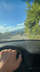 Driver adjusts controls while driving in Sveti Stefan, Montenegro