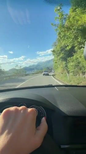 Driver adjusts controls while driving in Sveti Stefan, Montenegro
