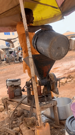 Man operates gasoline grinder under umbrella in Nigeria