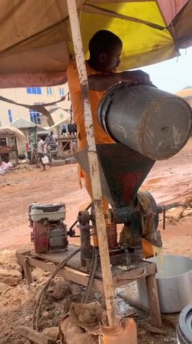 Man operates gasoline grinder under umbrella in Nigeria
