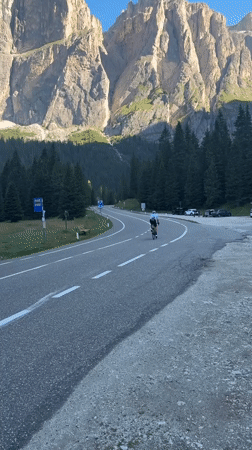 Sella Pass, Canazei: cyclist, road, and Alpine architecture