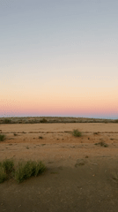 Rainbow spans Namibian desert landscape at dusk