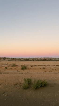 Rainbow spans Namibian desert landscape at dusk