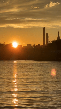 NYC skyline silhouetted against a warm waterfront sunset