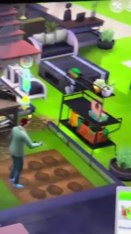 The video shows a screen playing the Sims video game. The view is of an outdoor area with a Sim, possibly male, standing near a garden plot with planting holes. The Sim is wearing a green jacket and blue shoes. To the left, there are raised garden beds with plants. There's also a large tree with yellow foliage. A workstation with drawers is visible near the garden area. Further back, there is outdoor furniture, a staircase, and other house elements. The bottom of the screen displays the game's interface, including the Sim's name and other information.