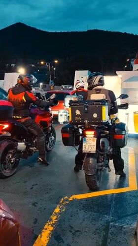 Motorcyclists cross Montenegro waters by ferry at dusk