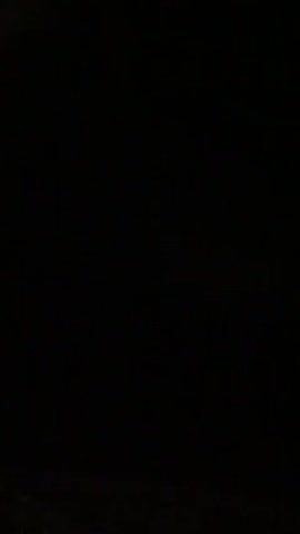 The video begins with blackness. A lightning strike illuminates a dark, stormy sky above a silhouetted treeline and landscape. The strike is brief, and the video returns to blackness.