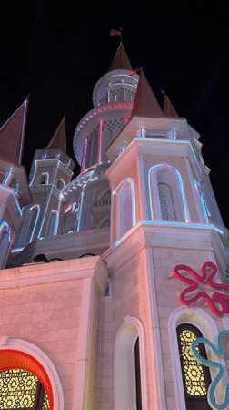 Crowds gather at a lit-up themed complex after dark